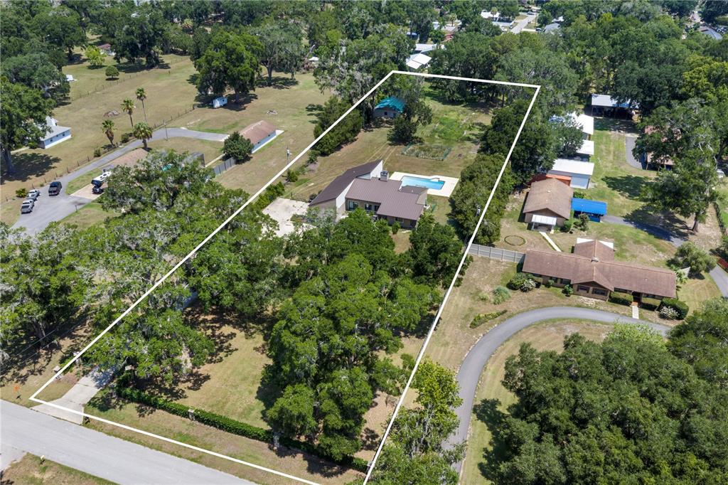 An aerial view shows a house with a pool on a large, tree-filled residential lot — 3261 SE 41ST PLACE, OCALA, FL