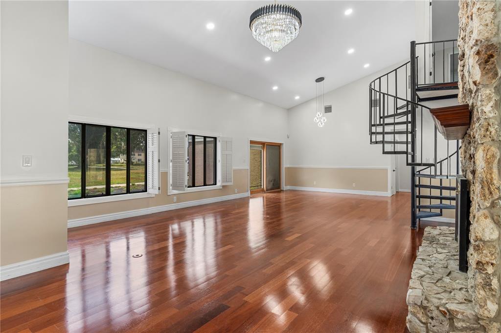 A spacious living room features hardwood floors, a stone fireplace, and a black spiral staircase — 3261 SE 41ST PLACE, OCALA, FL