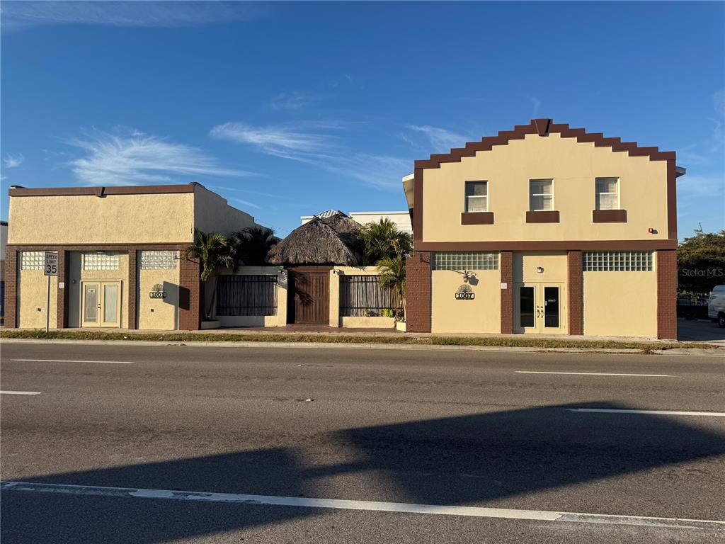 Two adjacent commercial buildings with tan stucco facades and brown trim stand along a road — 1007 MANATEE AVENUE E, BRADENTON, FL