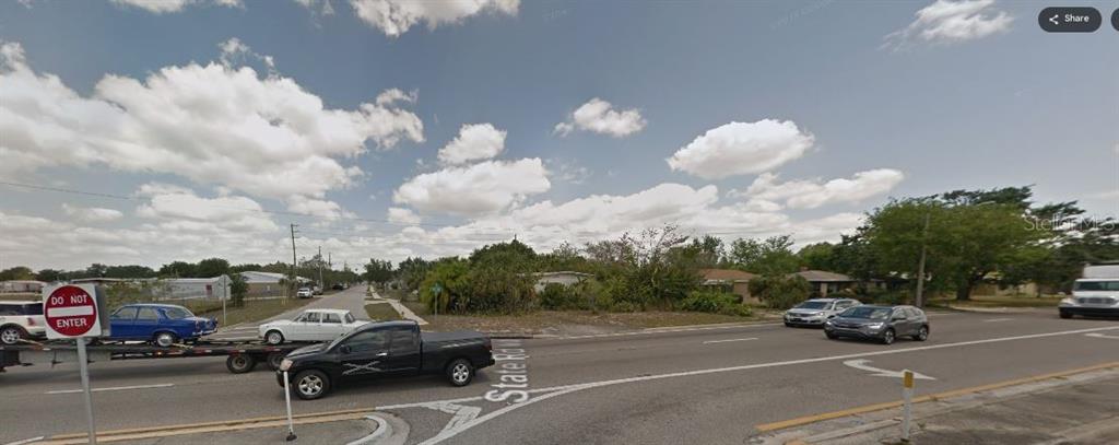 A street-level view of a vacant corner lot next to a road with passing traffic — SR-60, OKEECHOBEE, FL