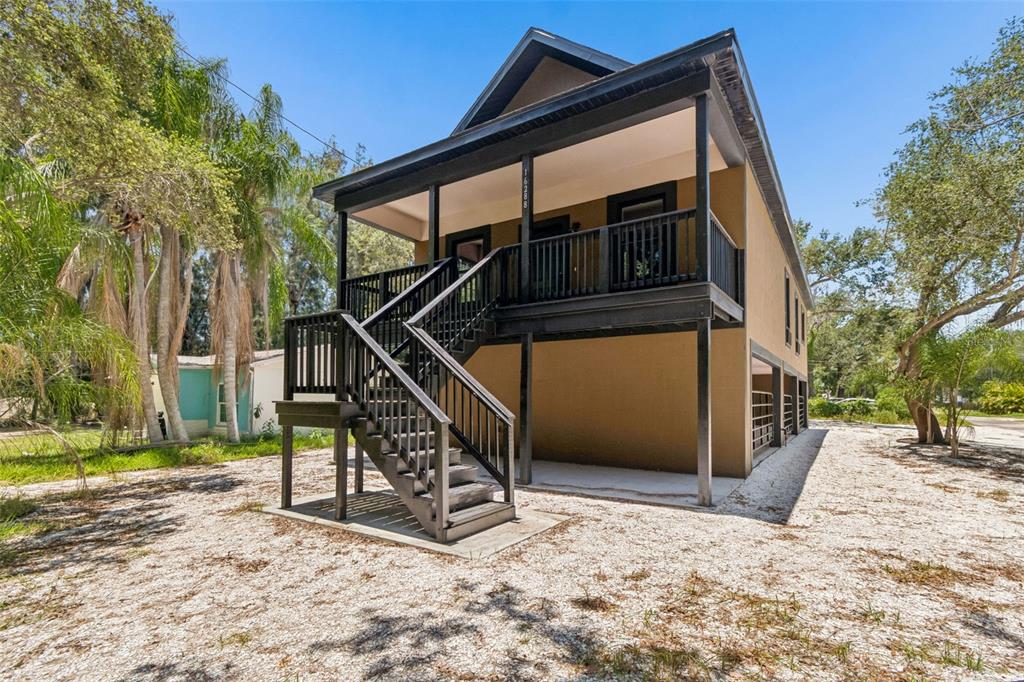 A two-story house with a raised porch, black railings, and an exterior staircase — 16288 48TH ST N, CLEARWATER, FL