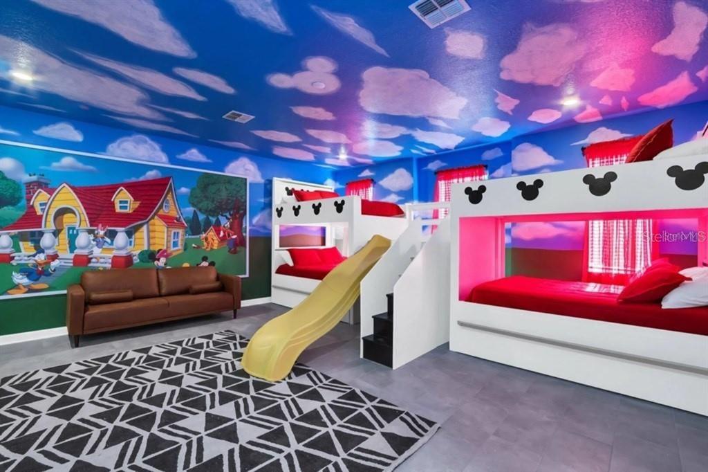 A themed bedroom features two bunk beds with slides, a brown sofa, and cloud-painted walls — 3000 PENELOPE LOOP, KISSIMMEE, FL