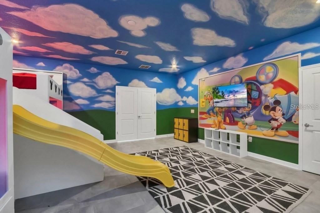 A themed children's playroom features a yellow slide, a Mickey Mouse mural, and cloud-painted ceilings — 3000 PENELOPE LOOP, KISSIMMEE, FL