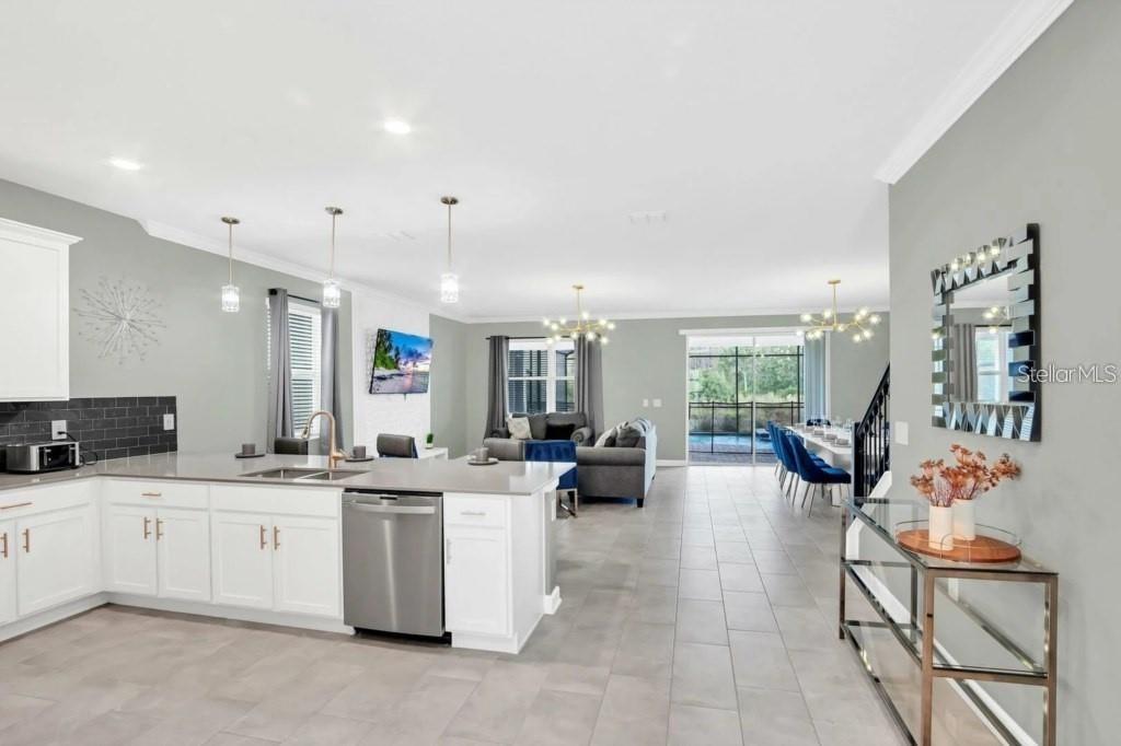An open-concept kitchen with white cabinets and a stainless steel dishwasher overlooks a living area — 3000 PENELOPE LOOP, KISSIMMEE, FL