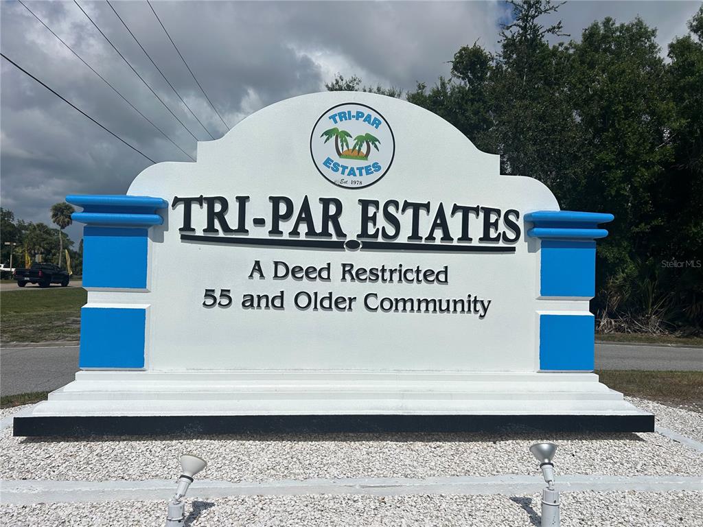 A white monument sign for Tri-Par Estates stands outdoors against a cloudy sky — 5007 BOCA RATON AVENUE, SARASOTA, FL