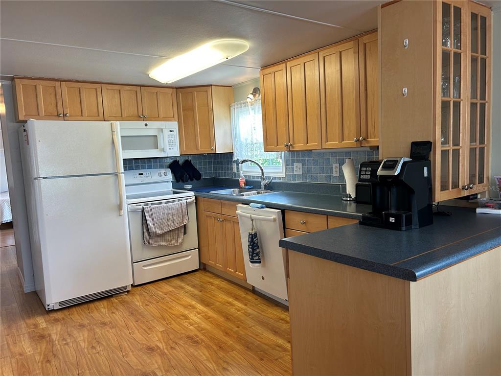 A kitchen features light wood cabinets, white appliances, blue countertops, and wood-look flooring — 5007 BOCA RATON AVENUE, SARASOTA, FL