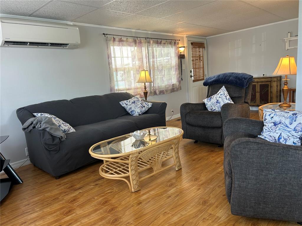 A living room features a dark sofa, two armchairs, a wicker coffee table, and wood flooring — 5007 BOCA RATON AVENUE, SARASOTA, FL