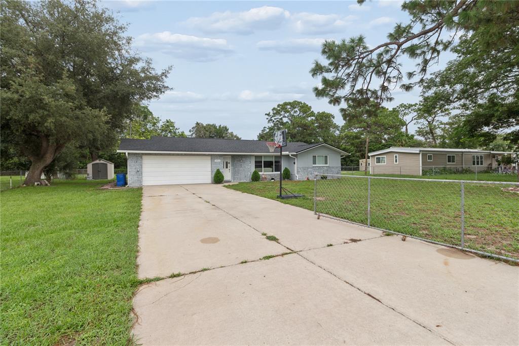 A single-story house with a white garage door, gray brick facade, and a concrete driveway — 9733 DICK STREET, HUDSON, FL