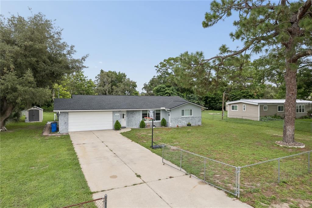 A single-story house with a white garage door, gray siding, and a concrete driveway — 9733 DICK STREET, HUDSON, FL