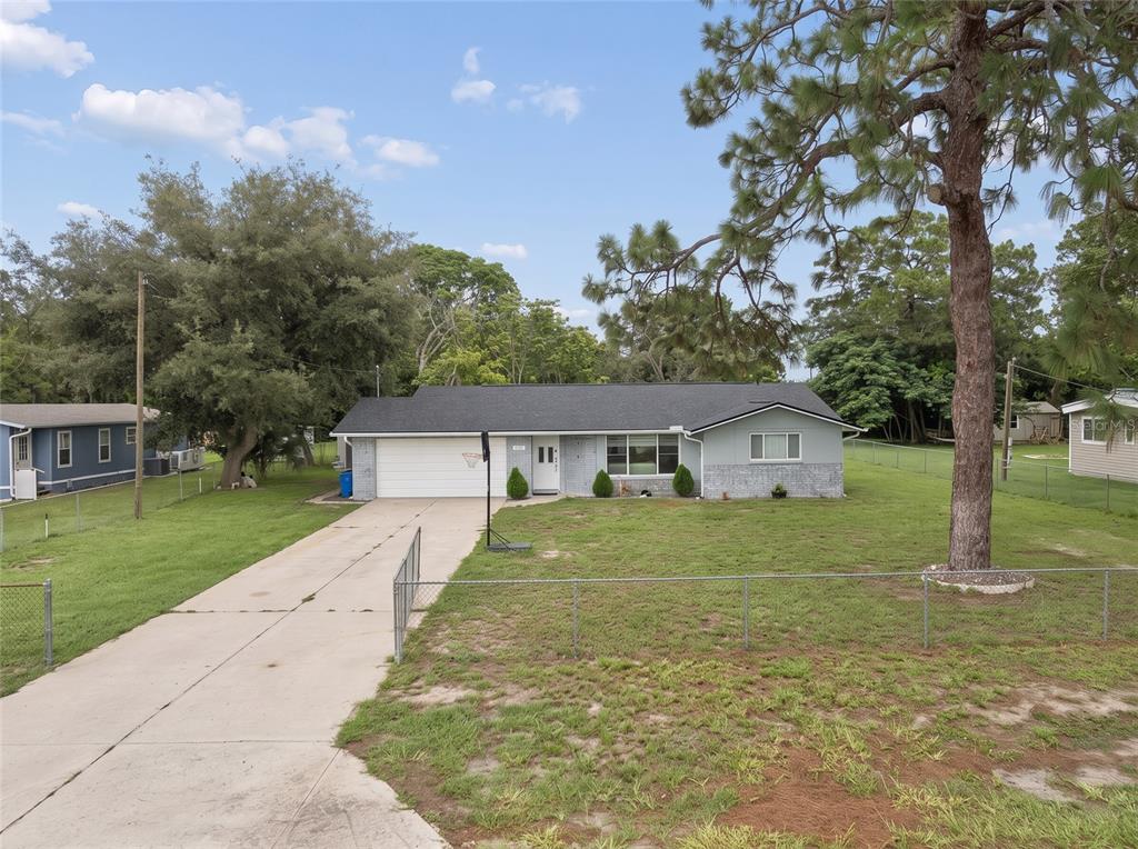 A single-story house with a white garage, gray siding, and a large front yard — 9733 DICK STREET, HUDSON, FL