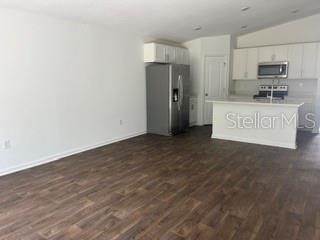 An open-concept kitchen features white cabinetry, stainless steel appliances, and wood-look flooring — 30 PONY LANE UNIT A, PALM COAST, FL