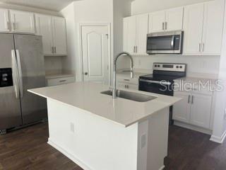 A modern kitchen features white cabinets, stainless steel appliances, and a central island with a sink — 30 PONY LANE UNIT A, PALM COAST, FL