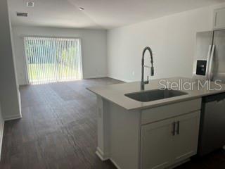 A kitchen island with a sink overlooks an open living area with sliding glass doors — 30 PONY LANE UNIT A, PALM COAST, FL