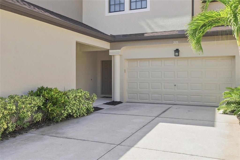 A beige house exterior features a concrete driveway, a garage, and a recessed front entrance — 3781 COSTA MAYA WAY UNIT 101, ESTERO, FL