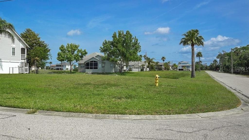 A vacant grassy lot sits on a corner next to a suburban street and houses — 4065 SHEEPHEAD DRIVE, HERNANDO BEACH, FL