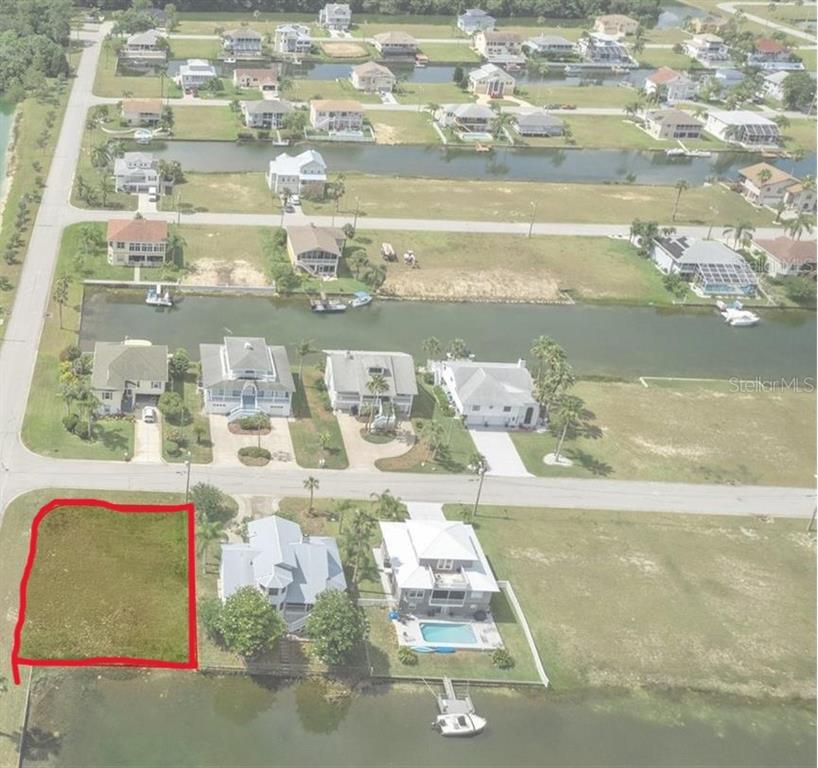 An aerial view shows a vacant waterfront lot outlined in red next to existing houses — 4065 SHEEPHEAD DRIVE, HERNANDO BEACH, FL