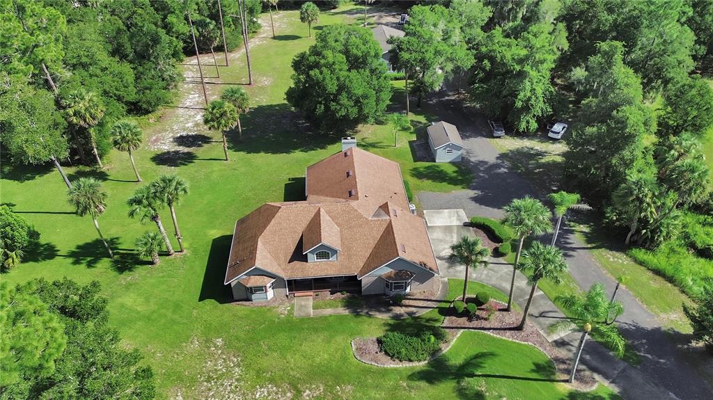 An aerial view of a house with a brown shingled roof surrounded by green trees — 1925 GLENWOOD OAKS LANE, DELAND, FL