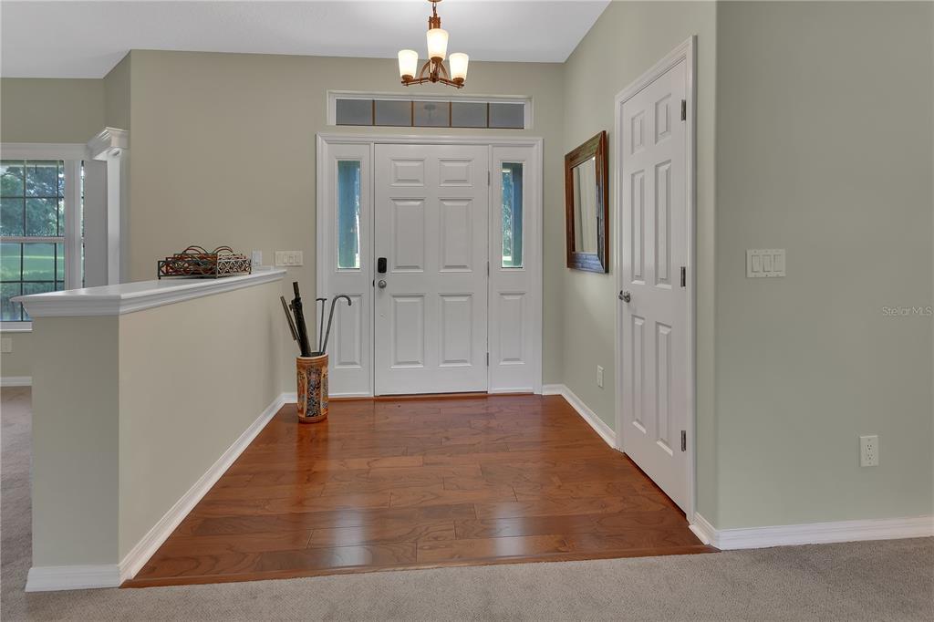 An entryway features hardwood flooring, a white front door with sidelights, and a half wall — 1925 GLENWOOD OAKS LANE, DELAND, FL