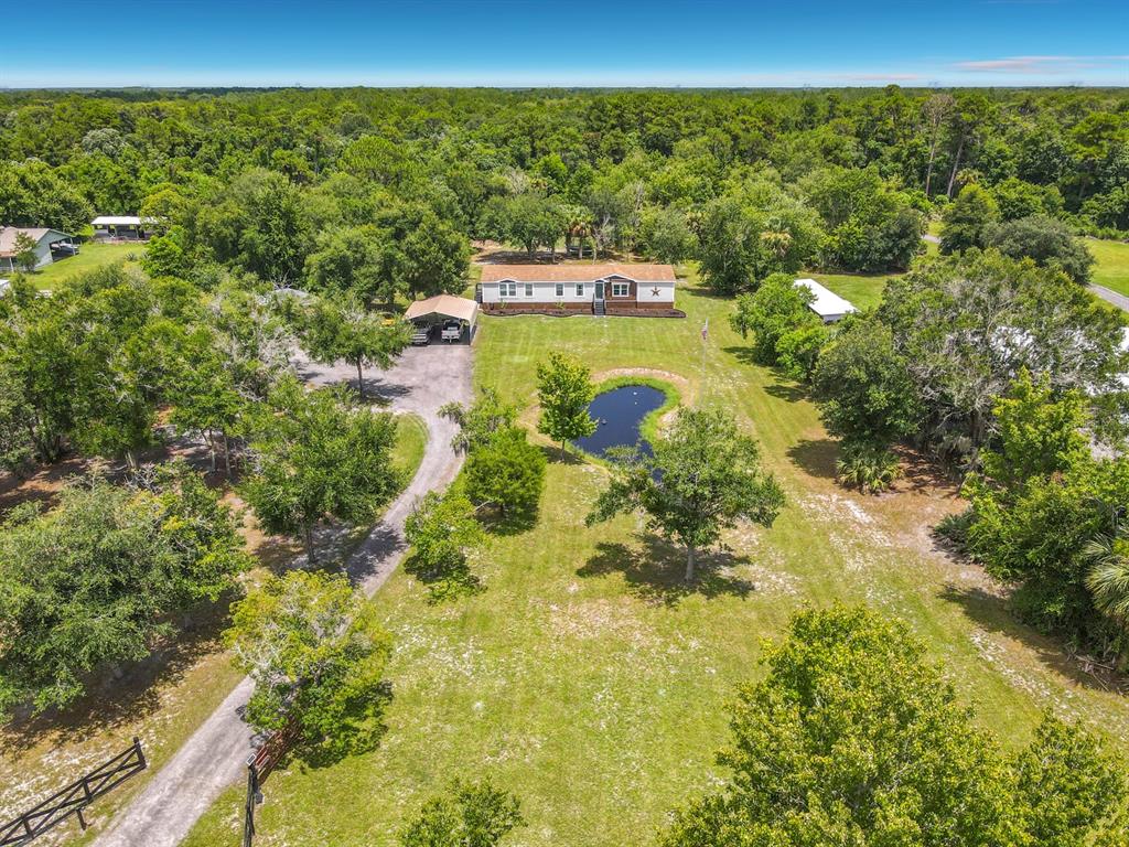 A red metal gate with a star emblem stands before a single-story manufactured home — 353 URANUS TRAIL, OSTEEN, FL