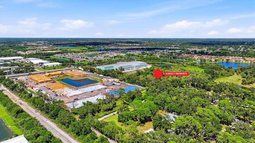 An aerial view shows a wooded lot marked as the subject property near new construction — 7845 27TH STREET E, SARASOTA, FL