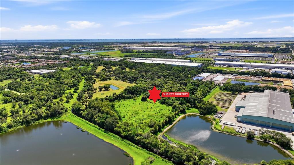 An aerial view shows a vacant, wooded lot marked with a red star near ponds — 7845 27TH STREET E, SARASOTA, FL