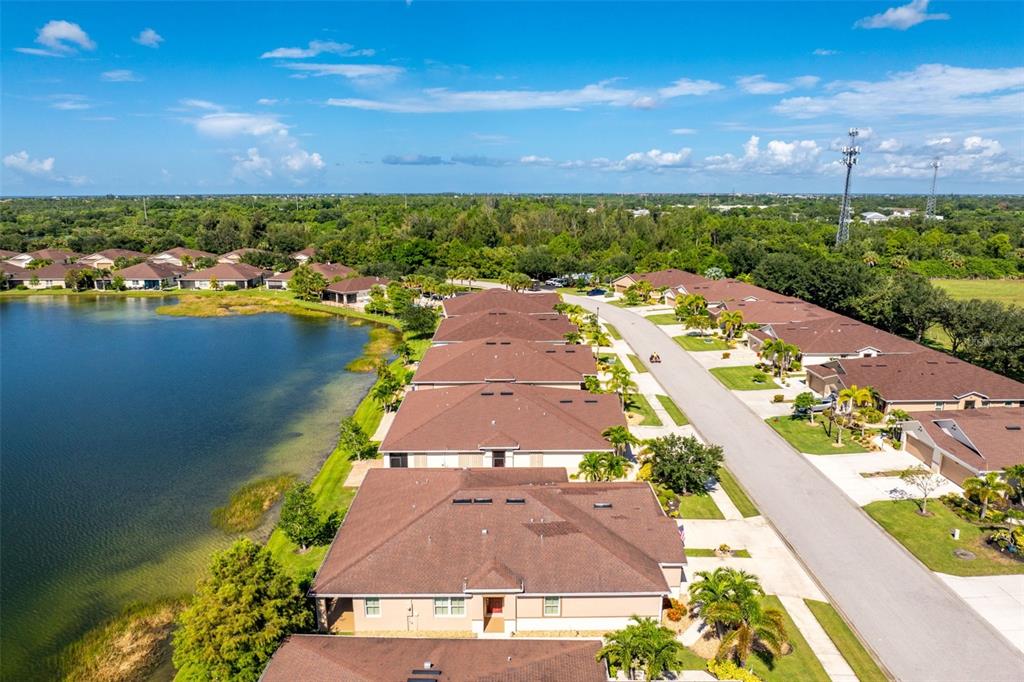 An aerial view shows a row of suburban houses along a lake and a street — 8849 TUSCANY ISLES DRIVE, PUNTA GORDA, FL