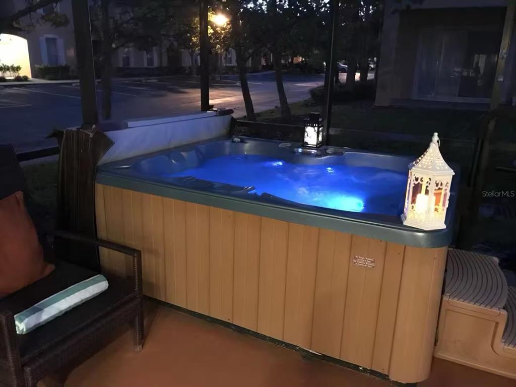 A screened-in patio features a hot tub, outdoor furniture, and a grill on a concrete floor — 2700 CAMARO DRIVE, KISSIMMEE, FL