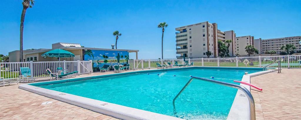 A rectangular swimming pool sits on a brick patio in front of a multi-story building — 2020 N ATLANTIC AVENUE UNIT 610N, COCOA BEACH, FL