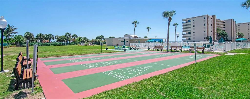 An outdoor shuffleboard court sits on a grassy lawn near a multi-story apartment building — 2020 N ATLANTIC AVENUE UNIT 610N, COCOA BEACH, FL