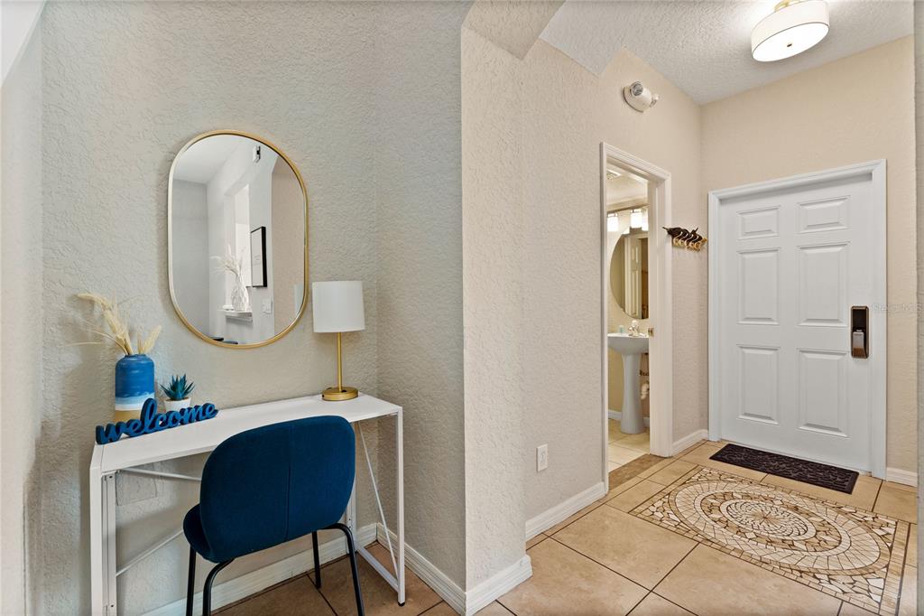 An entryway features a white desk, a blue chair, a mirror, and a tiled floor — 436 CALABRIA AVENUE, DAVENPORT, FL