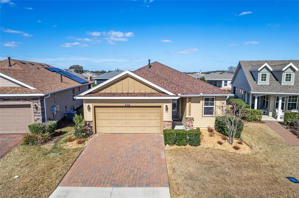 A tan single-story house with a brick driveway and a brown shingled roof — 5579 NW 40TH PLACE, OCALA, FL