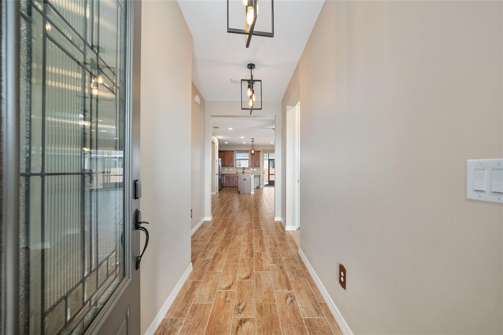 A hallway with wood-look tile flooring leads from a front door toward a kitchen — 5579 NW 40TH PLACE, OCALA, FL