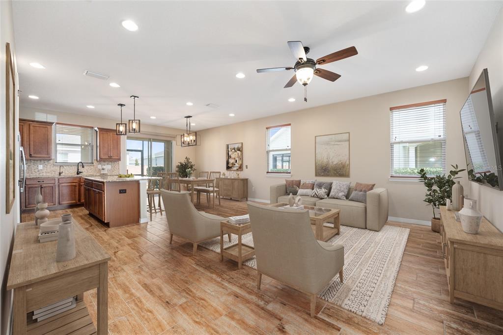 An open-concept living room and kitchen featuring wood-look tile flooring and neutral-toned furniture — 5579 NW 40TH PLACE, OCALA, FL
