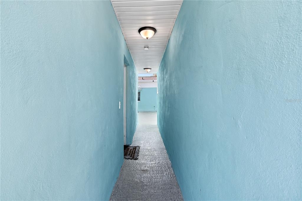 A narrow outdoor walkway with light blue stucco walls and a white paneled ceiling — 804 13TH AVENUE S, ST PETERSBURG, FL