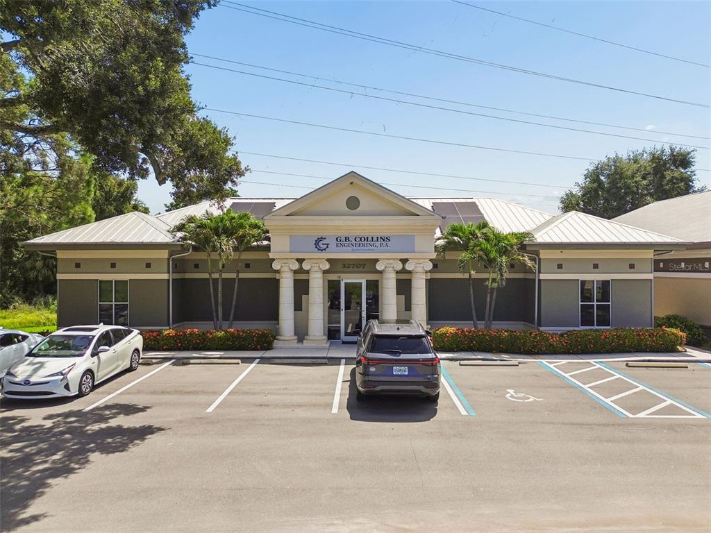 A single-story commercial building with a columned entrance and a parking lot in front — 32707 US HIGHWAY 19 N, PALM HARBOR, FL