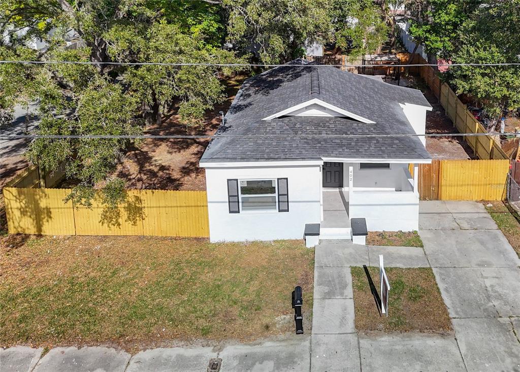 A white, single-story house with a black front door, shutters, and a yellow wooden fence — 402 E VIRGINIA AVENUE, TAMPA, FL