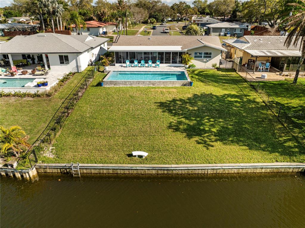 An aerial view of a waterfront house with a swimming pool and a large lawn — 632 SHORE DRIVE, LARGO, FL