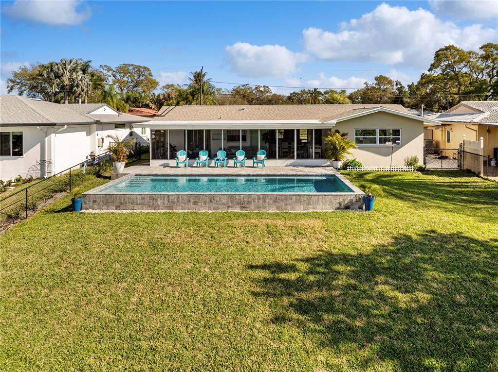 A backyard features a rectangular above-ground swimming pool and a house with a screened patio — 632 SHORE DRIVE, LARGO, FL