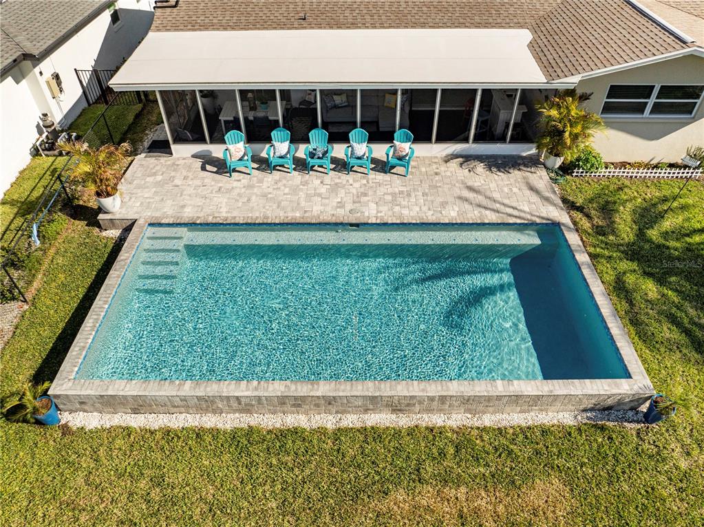 An aerial view shows a rectangular swimming pool with a paved patio and five chairs — 632 SHORE DRIVE, LARGO, FL