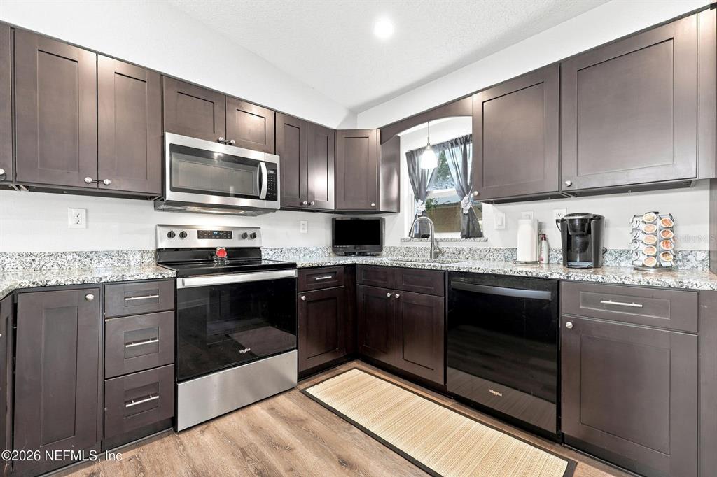 A kitchen features dark wood cabinets, granite countertops, and stainless steel appliances — 905 SAINT JOHNS AVENUE, GREEN COVE SPRINGS, FL