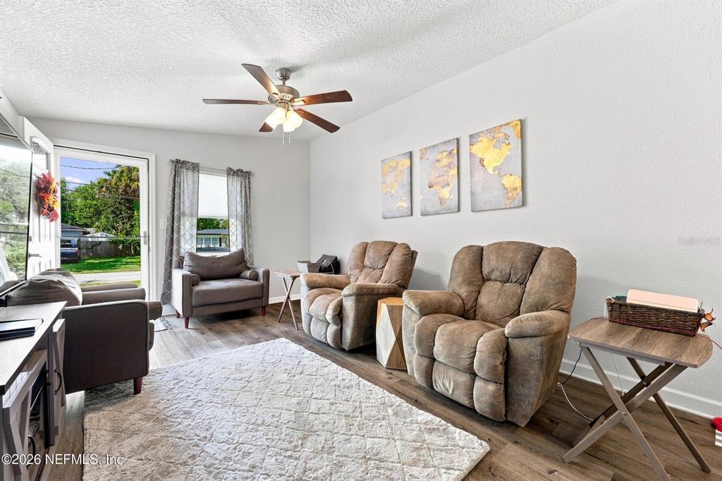 A living room features wood-look flooring, a ceiling fan, three recliners, and wall art — 905 SAINT JOHNS AVENUE, GREEN COVE SPRINGS, FL