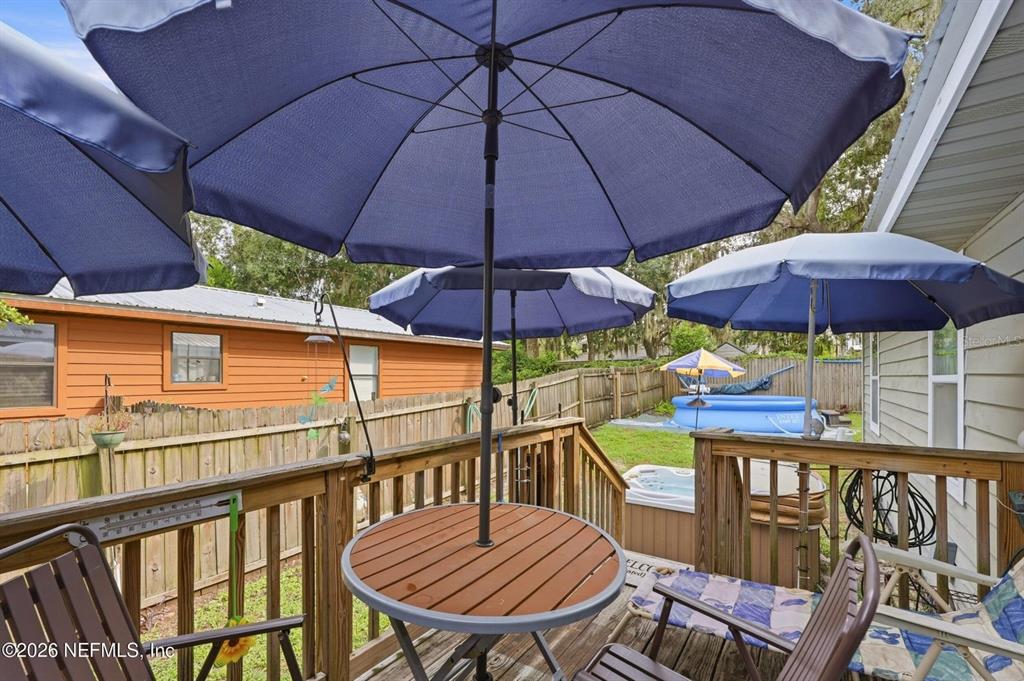 A wooden deck features a round table with a blue umbrella and a small pool — 905 SAINT JOHNS AVENUE, GREEN COVE SPRINGS, FL