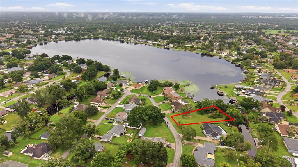 An aerial view shows houses surrounding a lake with private docks and lily pads — 22506 SHORESIDE DRIVE, LAND O LAKES, FL