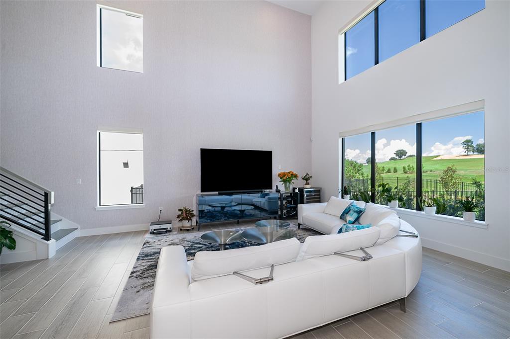 A living room with high ceilings, a white sectional sofa, and large windows overlooking a golf course — 16046 VOLTERRA POINT, BELLA COLLINA, FL