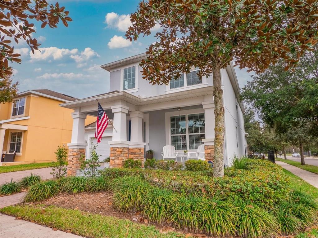 A covered front porch features stone-based columns, white rocking chairs, and a ceiling fan — 7537 BROFIELD AVENUE, WINDERMERE, FL