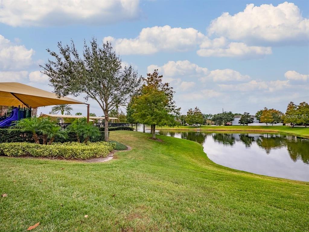 A playground with a blue slide and a large shade canopy over wood chip ground — 7537 BROFIELD AVENUE, WINDERMERE, FL