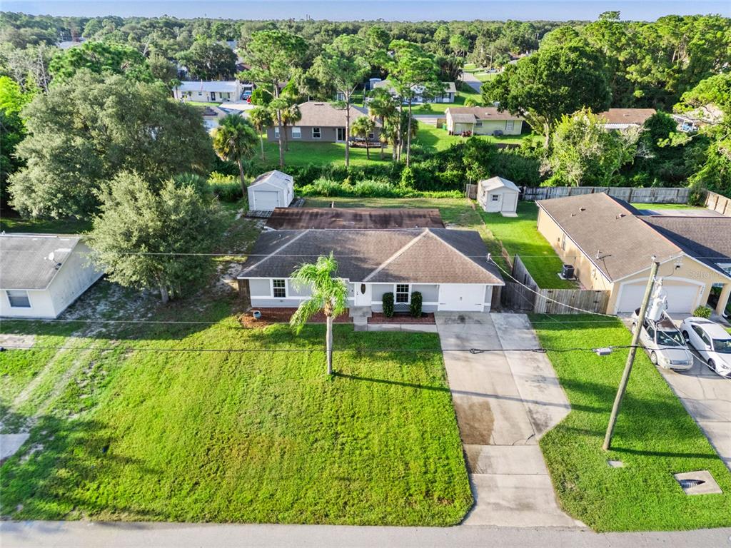 An aerial view shows a single-story house with a front lawn, driveway, and two sheds — 4790 GREENHILL STREET, COCOA, FL
