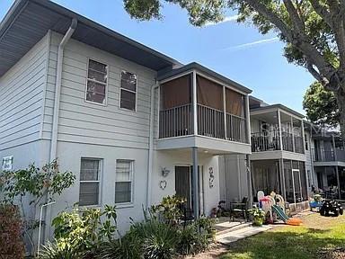A two-story apartment building features light gray siding and screened-in balconies on the upper level — 10800 US HIGHWAY 19 N UNIT 237, PINELLAS PARK, FL