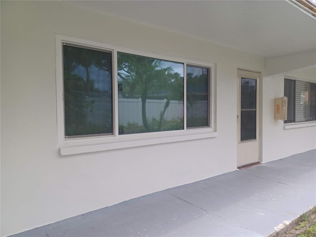 An outdoor swimming pool is surrounded by a white fence, palm trees, and apartment buildings — 2525 W BAY DRIVE UNIT A12, BELLEAIR BLUFFS, FL