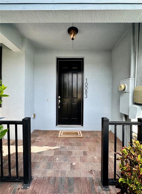 A front porch with a black door, brick pavers, and a light fixture above — 10083 EAGLE CREEK CENTER BOULEVARD, ORLANDO, FL